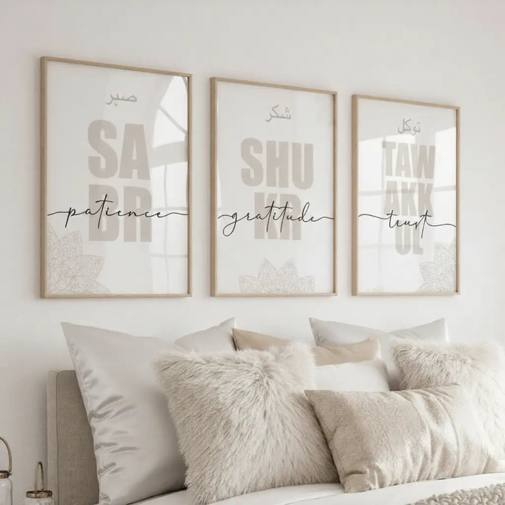 Three framed prints on a wall above a bed with pillows.