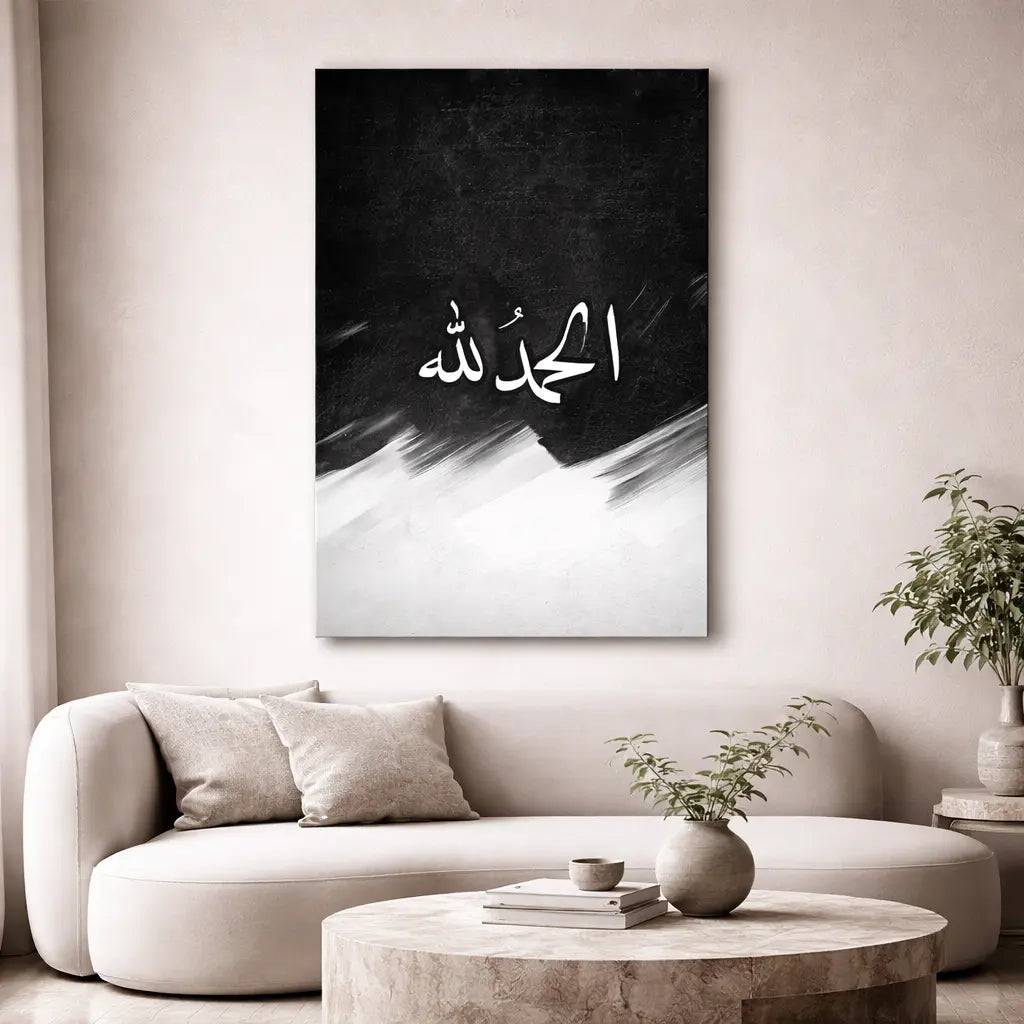 Modern living room with a white sofa, coffee table, and decorative plant. A black and white abstract painting with Arabic calligraphy is on the wall.