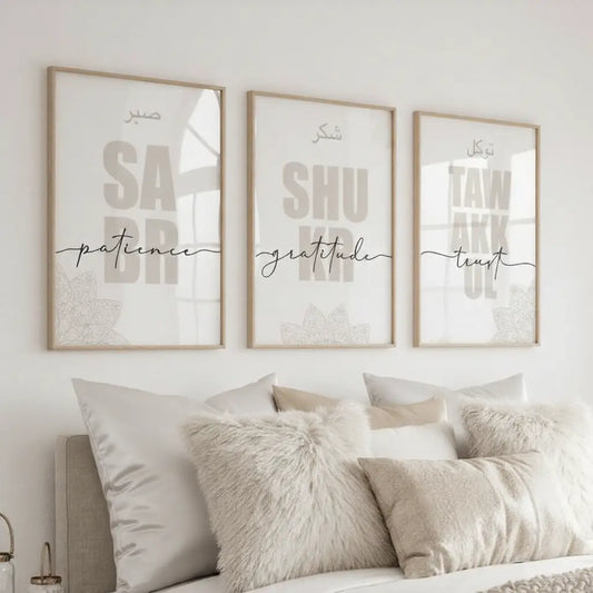 Three framed prints on a wall above a bed with pillows.